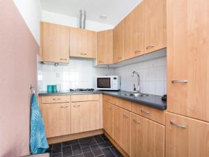 une cuisine avec des armoires en bois et un micro-ondes dans l'établissement Apartment in Julianadorp near the Beach, à Julianadorp