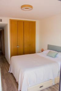 Un dormitorio con una gran cama blanca y armarios de madera. en Ático Premium con Azotea, Pádel y Piscina, en Sant Jordi (San Jorge)