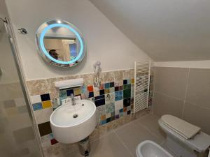 un bagno con lavandino, WC e specchio di IL CORSO apartment a Cesena Altre 17 foto