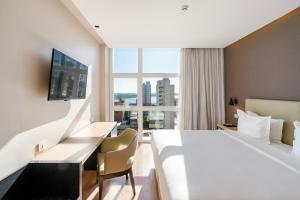 een hotelkamer met een bed, een bureau en een raam bij Palmaroga Hotel Asuncion, Tapestry Collection by Hilton in Asuncion