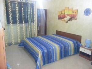 - une chambre dotée d'un lit avec une couverture bleue et jaune dans l'établissement B&B La Collina, à Collepasso