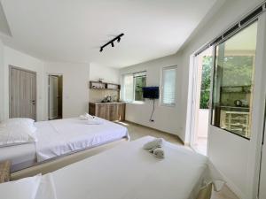 a white bedroom with two beds and a tv at Guest House Koliqi - Hotel & Apartments in Ulcinj