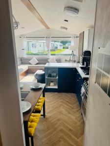 a kitchen with blue cabinets and a table with yellow seats at Haven cleethorpes beach holiday park in Cleethorpes