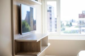 a living room with a tv on a wall with a window at Zeta Inn - Departamentos en pleno centro - Neuquén Capital in Neuquén