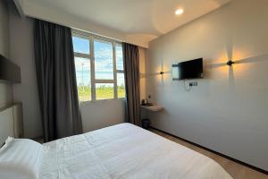 a bedroom with a white bed and a window at LeLian Hotel SIBUJAYA in Sibu