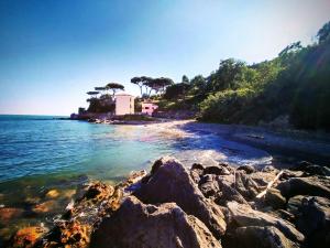a rocky beach with a house in the background at La Casa nel Carobio in Ameglia +6 photos