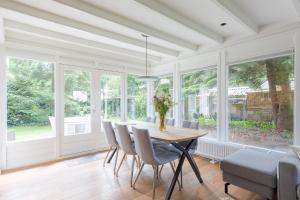 a dining room with a table and chairs and windows at De Das in Oldeberkoop