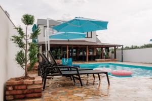 a table with a blue umbrella next to a swimming pool at Villa Cartagena 2 in Brčko