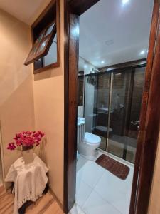 a bathroom with a toilet and a vase of flowers at Aconchego de Itaipava - casa de 3 quartos, equipada, área kids, jacuzzi, pet friendly, churrasqueira, em meio a Natureza e próximo ao centro do bairro in Araras Petropolis +37 photos