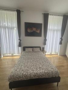 a bedroom with a bed and two large windows at Studio Lilia in Brussels