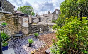 un jardín con mesa y sillas frente a un edificio en The Wonky Burrow, en Bowness-on-Windermere