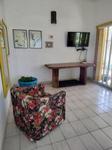 un soggiorno con un divano, un tavolo e una TV di Pé na Areia - Casa para temporada a São Sebastião