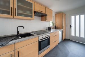a kitchen with wooden cabinets and a sink at Modernes Wohlfühl-Apartment in Solingen