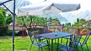 un tavolo blu e sedie sotto un ombrellone di Isola Bella a Ossuccio