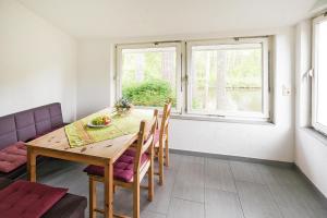 a dining room with a table and chairs and two windows at Ferienhaus Eldeblick direkt am Eldeufer in Parchim in Parchim