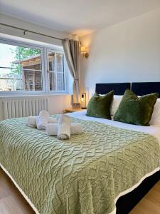 a bedroom with a large bed with green pillows at Four Counties Cottage in Collyweston by Amber Stays, Perfect for Getaways with Free Parking in Collyweston