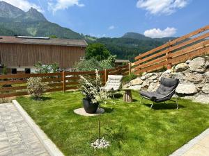 a yard with a chair and a rock fence at Beagzeit Ferienwohnung in Lofer