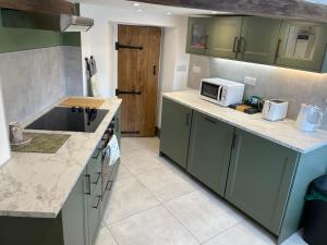 a kitchen with green cabinets and a microwave at Brock cottage Tideswell newly modernised in heart of Peak District National Park in Tideswell