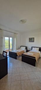 two beds in a room with a room with a window at Villa Violeta in Ksamil