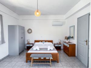 a white bedroom with a bed and a chair at Sea view Lefkes in Kithnos