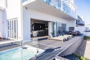 an outdoor deck with a swimming pool and a house at Jonesy's Place on the Beach in Yzerfontein