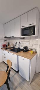 a kitchen with white cabinets and a microwave at Tiny Teo Sătic in Satic