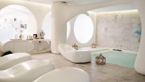 Un baño con bañera y dos sillas blancas y una bañera. en Dolce by Wyndham Siracusa - I Monasteri Golf & Spa, en Siracusa