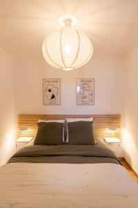 ein Schlafzimmer mit einem großen Bett und einem Kronleuchter in der Unterkunft Charmant appartement duplex, 6 personnes, 3 chambres, 2 salle de bains, dans Loudenvielle à 50m du skyvall in Loudenvielle