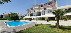 an apartment building with a swimming pool and a palm tree at Ölüdeniz Günlük Kiralık Daire & Apart havuzlu in Oludeniz