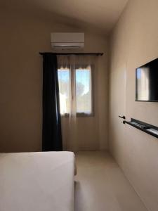a room with a window and a bed and a television at B&B Monstera SicilianExperience in San Corrado di Fuori