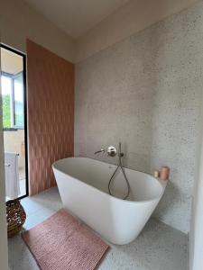 a white bath tub in a bathroom with a rug at B&B Monstera SicilianExperience in San Corrado di Fuori +24 photos