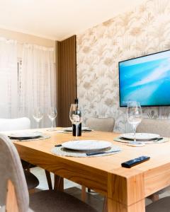 a dining room table with wine glasses and a flat screen tv at Firmat Apart Premium Estadías confortables para empresas y familias 2 in Firmat