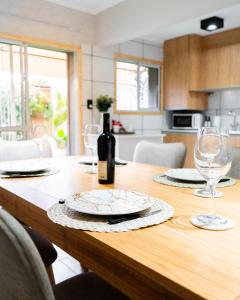 a wooden table with a bottle of wine and glasses at Firmat Apart Premium Estadías confortables para empresas y familias 2 in Firmat