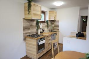 a kitchen with wooden cabinets and a stove top oven at Hamvas Vendégház Tiszakécske in Tiszakécske