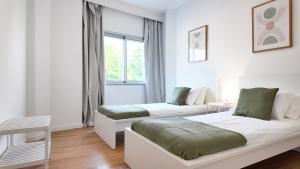 a white room with two beds and a window at Green House Apartamento Espaçoso e Central in Porto