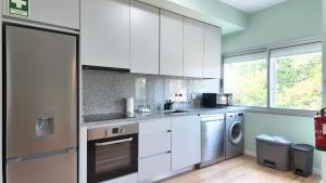 a kitchen with white cabinets and a washer and dryer at Green House Apartamento Espaçoso e Central in Porto +5 photos