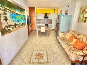 a living room with a couch and a kitchen at Casa Vacanze Porto Ainu in Tanaunella