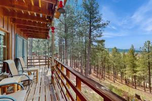 a deck with chairs and tables and a view of trees at Bigfoot Lodge in Angel Fire