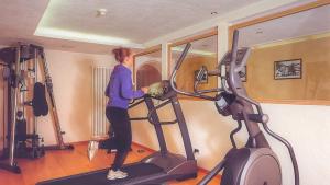 a woman standing on a treadmill in a gym at Hotel Resa Blancia in San Vigilio Di Marebbe