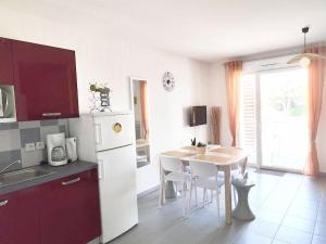 a kitchen with a white refrigerator and a table with chairs at Apartment 4-6 personnes avec Piscine Demeure De la Massane in Argelès-sur-Mer