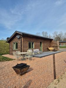a log cabin with a table and chairs in front of it at Birch Banc Retreats - Bedw Cabin 