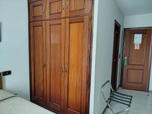 a bedroom with wooden cabinets and a chair next to a bed at Hotel Camiño de Santiago in Val do Dubra