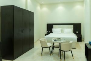 a bedroom with a bed and a table and chairs at شقق أون يسن للشقق المخدومة On Yassen Apartments Serviced in Unayzah