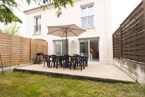 a patio with a table and chairs and an umbrella at Villa Cosy avec Jardin Paris Disney in Bry-sur-Marne