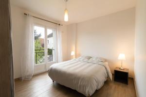a white bedroom with a bed and a window at Villa Cosy avec Jardin Paris Disney in Bry-sur-Marne