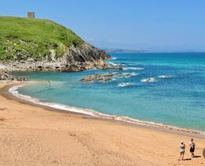 two people standing on a beach near the ocean at Ocean Suances in Suances