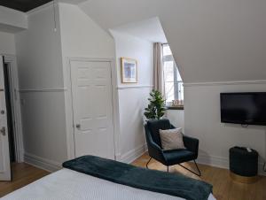 a bedroom with a bed and a chair and a television at Aux petits oiseaux in Baie-Saint-Paul