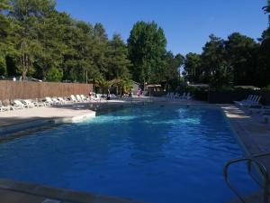 a swimming pool with chairs and blue water at La Margotine Mobil Home Cosy Plage et Dunes Camiers in Camiers +15 photos