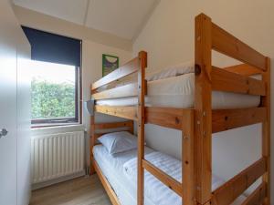 two bunk beds in a room with a window at Family Home by the Dunes in Sint Maartensvlotbrug