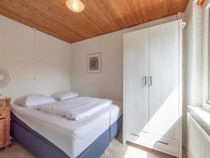 a small bedroom with a bed and a cabinet at Bungalow in Callantsoog near Sandy Beach in Callantsoog